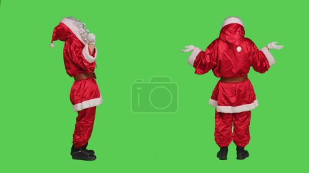 Photo for Father christmas praying to jesus on camera, wearing iconic red suit and white beard in studio. Santa claus pray to lord being spiritual and religious, traditional xmas winter celebration. - Royalty Free Image