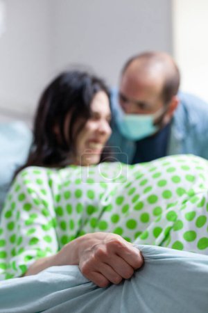 Foto de Mujer embarazada tratando de dar a luz al bebé en la sala del hospital, teniendo marido a su lado durante la cirugía de cesárea. Paciente con embarazo que tiene contracciones paniful durante el parto en la clínica de maternidad - Imagen libre de derechos