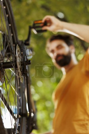 Photo for Close-up of bicycle rear derailleur and cogset being serviced and adjusted outside for leisure cycling. Detailed image of bike components being maintained and tested outdoor by sports-loving caucasian - Royalty Free Image