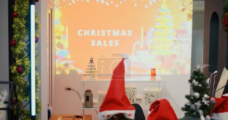 Photo for Revealing dolly in shot of digital screen billboard with Christmas sales advertisement written on it, promoting festive promotional offers in xmas adorn fashion boutique during winter holiday season - Royalty Free Image