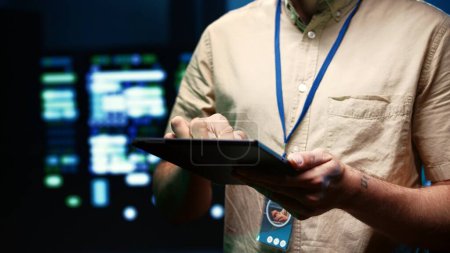 Photo for Close up shot of expert doing routine system review, adding data on tablet of needed mendings in server clusters housing advanced data storage infrastructure supporting critical IT workloads - Royalty Free Image