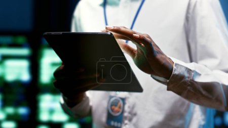 Foto de System administrator using tablet to check high tech facility security features protecting against unauthorized access, data breaches, phishing attacks and other cybersecurity threats, close up - Imagen libre de derechos