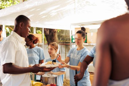 Foto de Al aire libre, diversos equipos de voluntarios distribuyen alimentos gratuitos a las personas necesitadas, incluidas las personas sin hogar y los refugiados. Su servicio compasivo proporciona apoyo vital a los desfavorecidos. - Imagen libre de derechos