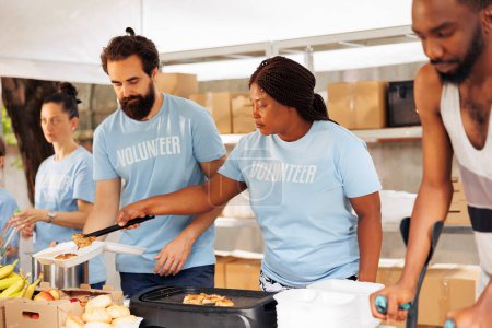 Foto de Voluntarios multiétnicos que proporcionan ayuda humanitaria, donan artículos esenciales y cocinan para los necesitados y los menos afortunados. Equipo de socorro del hambre que ayuda a las personas sin hogar, enfermas y empobrecidas. - Imagen libre de derechos