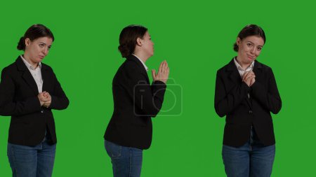 Foto de Primer plano del empleado corporativo haciendo oración manos firmar en la cámara, orando a Dios pidiendo suerte. Persona religiosa espiritual de pie en silencio sobre el fondo de la pantalla verde, la esperanza y la creencia. - Imagen libre de derechos
