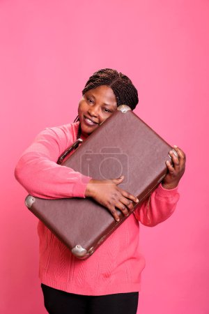 Photo for Cheerful model preparing suitcase baggage to leave on trip, travelling abroad to go on holiday vacation journey. Excited happy african american adult holding voyage luggage to do adventure. - Royalty Free Image