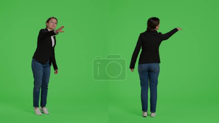Photo for Office accountant advertising wave to call someone over, asking for person to come in studio. Female manager in suit raising hand standing over full body isolated greenscreen background. - Royalty Free Image