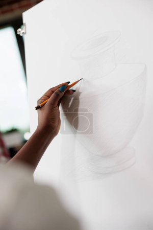 Foto de Primer plano de la mano femenina sosteniendo el lápiz aprendiendo a dibujar y dibujar mientras estudia en la escuela de arte. Personas que se expresan a través del dibujo, pasatiempos creativos y salud mental - Imagen libre de derechos