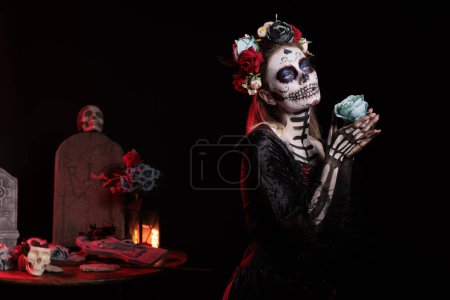 Photo for Spooky santa muerte model posing with roses over black background, looking like goddess of death. Beautiful woman with skull make up and body art, festival holiday celebration in studio. - Royalty Free Image