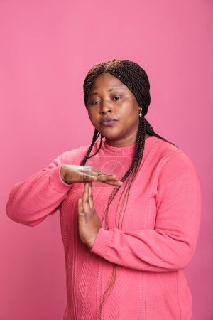 Photo for Disapproval negative woman doing timeout and break gesture while making displeased expression in studio, holding handd in t shape sign. Serious young woman advertising refuse in studio - Royalty Free Image