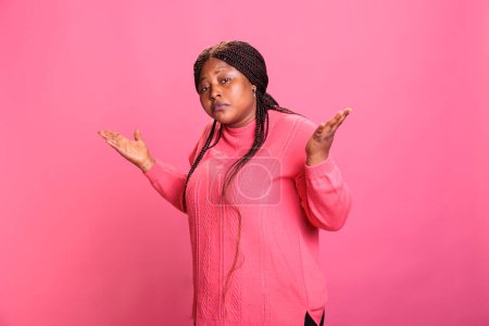 Photo for Doubtful young adult raising shoulder and being uncertain about answer, doing i dont know sign over pink background. Clueless indecisive model expressing confusion having unknown expression - Royalty Free Image