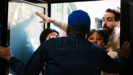 Photo for Security officer holding back clients at door entrance on black friday, trying to enter clothing store at mall. Anxious mad people searching for special offers and half price clothes. Handheld shot. - Royalty Free Image