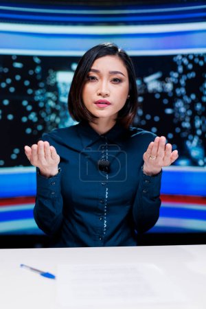 Photo for Broadcaster hosting night show live on television channel, discussing about latest celebrity scandals and global trends. Woman newscaster delivering breaking news headlines on tv program. - Royalty Free Image