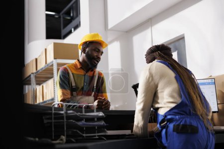 Photo for Logistics managers checking merchandise inventory on computer at warehouse reception desk. African american industrial storehouse workers planning cargo stock management in storage room - Royalty Free Image