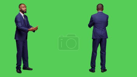 Photo for Young adult in suit having symphony concert at opera, conducting choir music posing over green screen backdrop. Optimistic conductor working as choirmaster having musical event in studio. - Royalty Free Image
