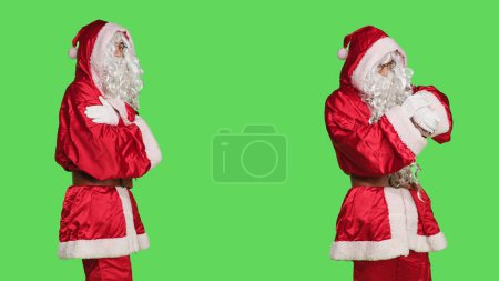 Téléchargez les photos : Modèle habillé comme Santa Claus attente, agissant impatient sur fond d'écran vert en studio. Jeune homme en costume traditionnel rouge cosplay agissant festif, attendre quelque chose. - en image libre de droit