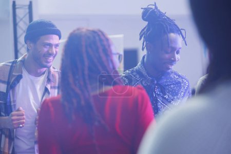 Photo for Group of smiling cheerful friends socializing and partying in nightclub. Carefree diverse people dancing and chatting on dancefloor while clubbing at social gathering event - Royalty Free Image