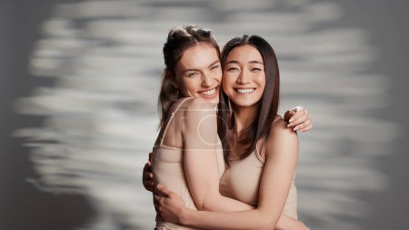 Happy diverse friends posing in studio for campaign, advertising self confidence and wellness products. Smiling girls with different skintones promoting diversity and body positivity.