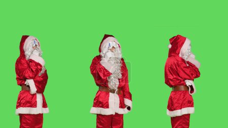 Photo for Thoughtful man in santa claus suit thinking about list of gifts, brainstorming session for presents ideas. Saint nick character with hat and white beard being pensive over greenscreen backdrop. - Royalty Free Image