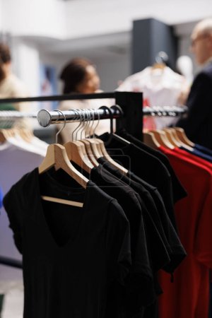 Photo for Close up of summer clothing hanging on clothes rail in modern fashion boutique, selective focus. T-shirts hang on cloth rack in outlet store. Seasonal shopping and retail business concept - Royalty Free Image