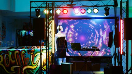 Photo for Club with mixing station and lights, audio sound panel on stage used for dj at disco party with funky music. Empty dance floor at discotheque, fun live performance at nightclub. Handheld shot. - Royalty Free Image