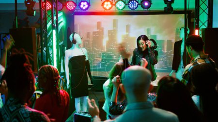 Téléchargez les photos : DJ féminin s'amusant sur scène de boîte de nuit, créant une ambiance funky clubbing sur la piste de danse. Jeune femme mélangeant de la musique électronique à une fête disco pour célébrer l'événement. Coup de main. - en image libre de droit