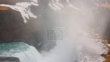 Téléchargez les photos : Cascade de Gullfoss à Reykjavik vers mars 2023 avec un débit d'eau spectaculaire et des paysages glaciaires. Rivière majestueuse en cascade près de falaises et de champs enneigés gelés, vue panoramique. - en image libre de droit