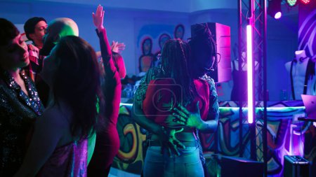 Photo for Young partners dancing in pairs at party, moving on dance floor and partying at nightclub. Couples having fun with romantic slow music at disco party, colorful lights club. Handheld shot. - Royalty Free Image