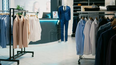 Photo for Trendy clothing store in empty shopping center, various brands with new modern clothes collection. Formal wear shirts and pants on racks, sale discount and commercial activity in retail shop. - Royalty Free Image