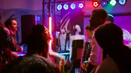 Photo for Diverse adults having fun at party showing dance moves on funky music, enjoying social gathering event. Men and women dancing on dance floor, feeling happy at discotheque. Handheld shot. - Royalty Free Image