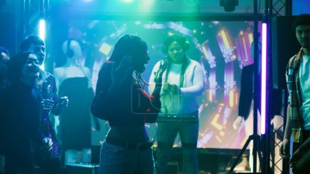 Photo for Young persons improvise dance battle and partying at nightclub, having fun with breakdance battle to show off skills. Group of friends enjoying dance party in modern discotheque. Tripod shot. - Royalty Free Image