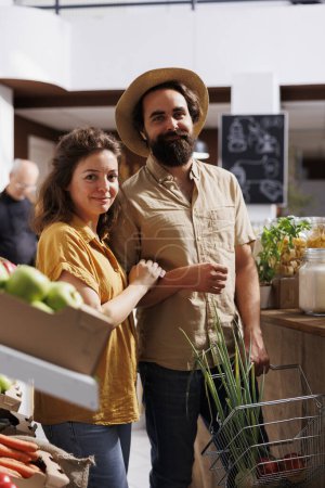 Photo for Husband and wife shopping in zero waste store, looking for healthy locally sourced bulk products. Green living couple purchasing pantry staples from local neighborhood shop - Royalty Free Image