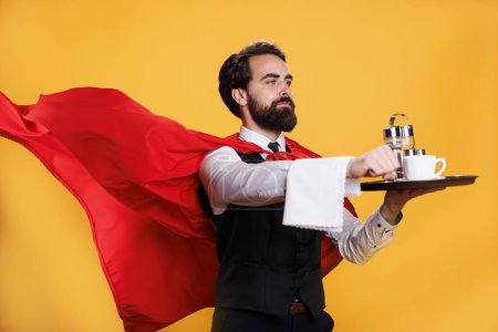 Photo for Elegant butler carry plate to serve dinner, wearing red superhero cape against yellow background. Professional waiter at restaurant holding food tray, showcasing powerful occupation. - Royalty Free Image