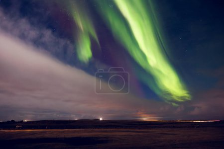 Foto de Hermosa aurora boreal cielo en iceland, espectaculares luces verdes y violetas del norte que aparecen por la noche creando paisaje panorámico. Brillante fenómeno mágico natural bajo el cielo estrellado. - Imagen libre de derechos