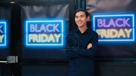 Photo for Clothing store customer on black friday enjoying special offers and big promotions, looking for clothes at half price. Asian shopper entering outlet boutique with discount banners. - Royalty Free Image