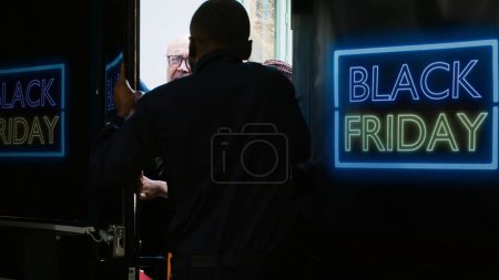Photo for Mad clients breaking into shop during black friday sales at department store, pushing security agent and forcing to enter outlet. Crazy aggressive customers outside shopping center. Tripod shot. - Royalty Free Image