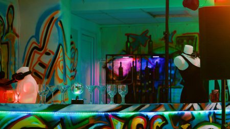 Téléchargez les photos : Plusieurs boissons alcoolisées au bar lors d'une fête funky underground, piste de danse vide à la boîte de nuit. Discothèque préparée pour l'événement de danse avec DJ mixant performance et spectacle de musique live. - en image libre de droit