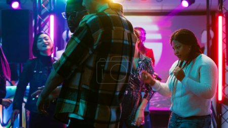 Foto de Grupo multiétnico de personas bailando, sintiéndose funky en la música en el club. Amigos disfrutando de actuaciones en vivo en pista de baile, mostrando movimientos de baile bajo luces de discoteca y fiesta. Trípode tiro. - Imagen libre de derechos