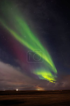 Photo for During wintertime, famous northern lights spotted over hills covered with snow. Icelandic magical aurora borealis create incredible show that brighten up cold night sky with stars. - Royalty Free Image