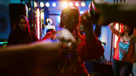 Photo for POV of woman dancing with man at party, enjoying disco music on dance floor. Diverse people having fun at nightclub listening to funky beats, social gathering celebration. Handheld shot. - Royalty Free Image