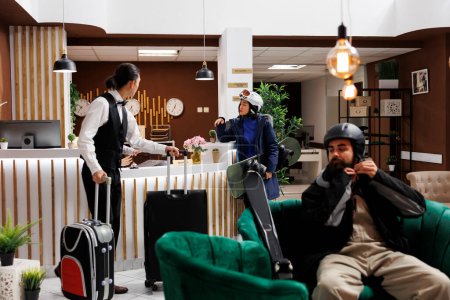 Photo for Arrival at modern hotel lobby, check-in, cozy lounge, luxury resort, winter gear, recreation, relaxation, exclusive holiday. Youthful tourists in lounge area awaiting accommodation. - Royalty Free Image