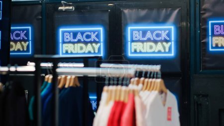 Photo for Empty fashion department store with sales and discounted items, retail shop with clothes on hangers. Black friday advertisement during november seasonal promotions, special offers sign. - Royalty Free Image
