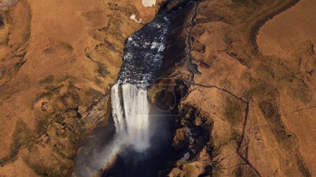 Téléchargez les photos : Vue aérienne d'une énorme cascade de glace, le débit de la rivière descend des collines gelées naturelles. Belle cascade de skgafoss nordique coulant des falaises formant des paysages glaciaires étonnants. Mouvement lent. - en image libre de droit