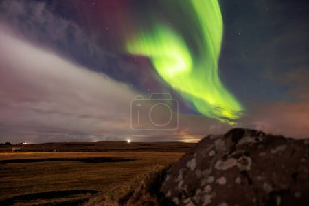 Photo for Aurora borealis above snowy mountain in winter landscape. Northern lights in Iceland creating beautiful natural phenomenon under night sky glowing. Polar scenery with magical reflection. - Royalty Free Image