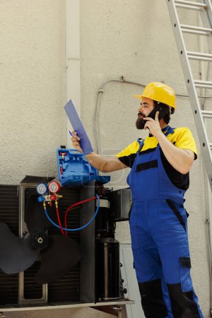 Photo for Adept repairman on the phone with client reporting found concerns about condenser during comissioned troubleshooting. Electrician going over hvac system warranty details with customer while on call - Royalty Free Image