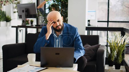 Analytiker, der mit Kopfschmerzen im Büro arbeitet, sich unwohl und überarbeitet im leitenden Job fühlt. Kranker Geschäftsmann kann wegen schmerzhafter Migräne nicht richtig denken, Projekt Burnout.