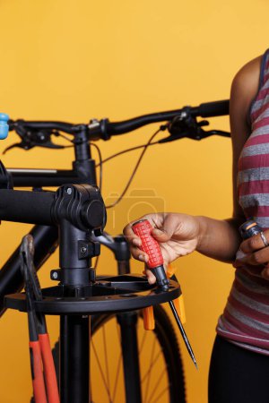 Téléchargez les photos : Plan détaillé de la personne afro-américaine choisissant des outils de travail experts pour l'entretien annuel du vélo. Image montrant la vue rapprochée des mains serrant tournevis pour la réparation de vélos modernes. - en image libre de droit
