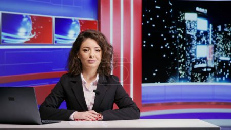 Photo for Media reporter presenting news on night show, discussing about latest events on television program in news studio. Woman journalist addressing daily newscast, hosting talk show for entertainment. - Royalty Free Image