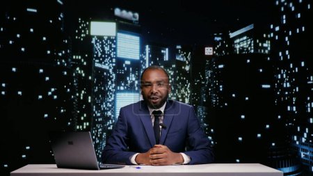 Photo for Happy tv host starting night talk show in newsroom, presenting world news and daily events live. African american man broadcasting news segment on midnight television program, reportage. - Royalty Free Image
