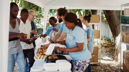 Foto de En un banco de alimentos, los voluntarios proporcionan asistencia a los desfavorecidos. Las personas voluntarias distribuyen alimentos donados con un comportamiento cálido, encarnando la esencia de los esfuerzos comunitarios y caritativos. - Imagen libre de derechos